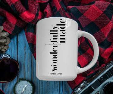 White mug with text on a red and black plaid fabric background