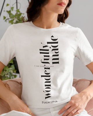 Woman wearing a white t-shirt with text design, sitting on a chair.