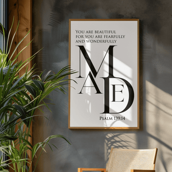 Framed artwork with text on a wall next to a plant