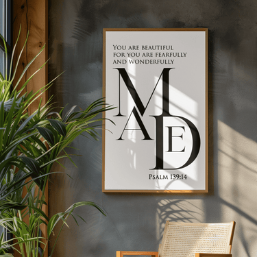 Framed artwork with text on a wall next to a plant