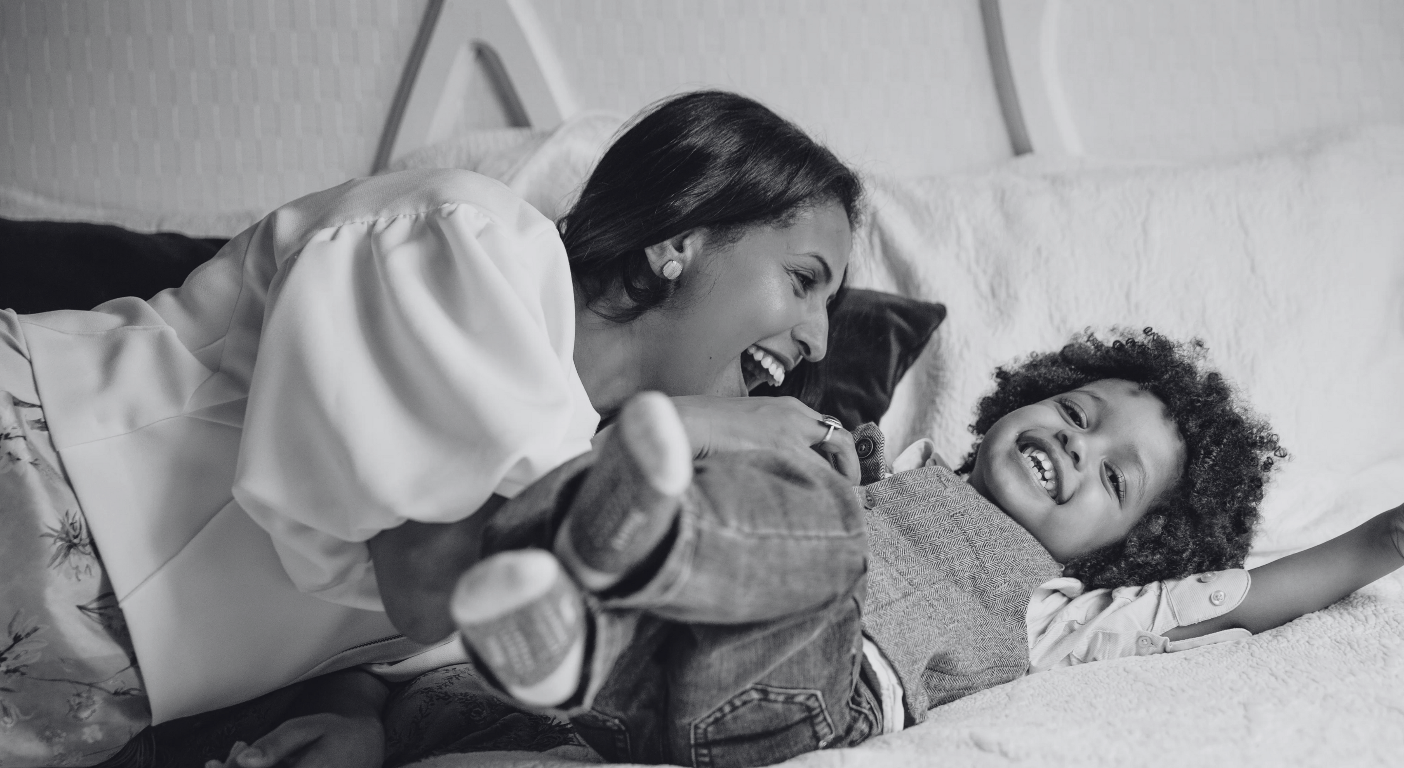 Joyful mother playing with her child on bed – lifestyle image representing family, faith, and connection