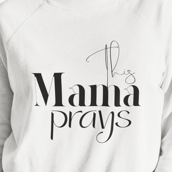 White sweatshirt with 'This Mama Prays' text on a plain background