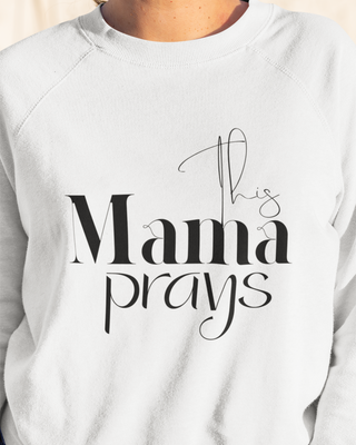 White sweatshirt with 'This Mama Prays' text on a plain background
