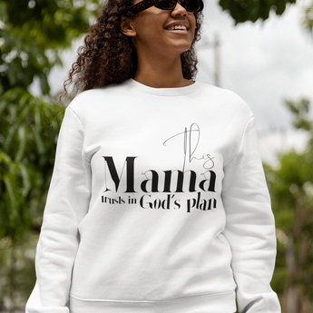 Woman wearing a white sweatshirt with text, standing outdoors with greenery in the background